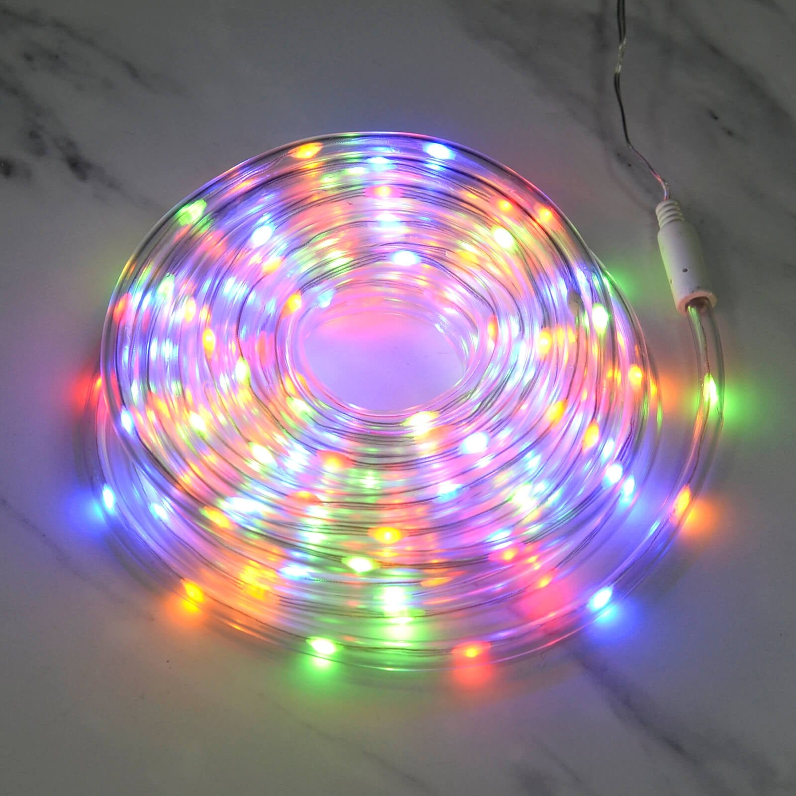 multicoloured rope light fro Christmas decoration lit up in a coil on a marble floor